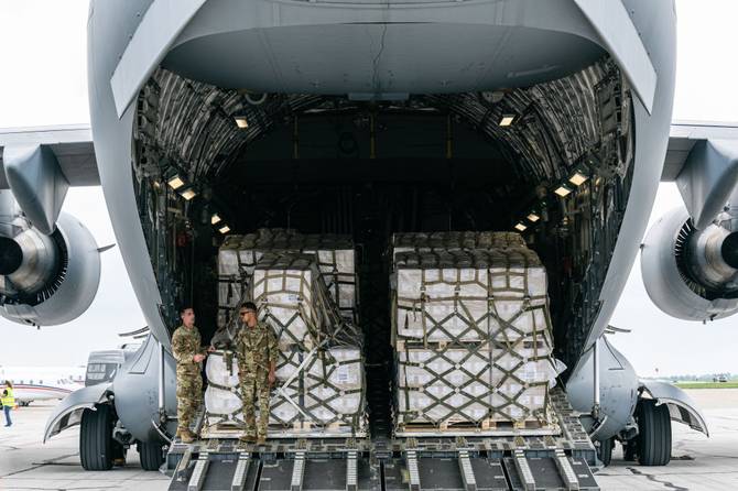 Airmen stand in the cargo bay of a U.S. Air Force C-17 carrying 78,000 lbs of Nestlé Health Science Alfamino Infant and Alfamino Junior formula