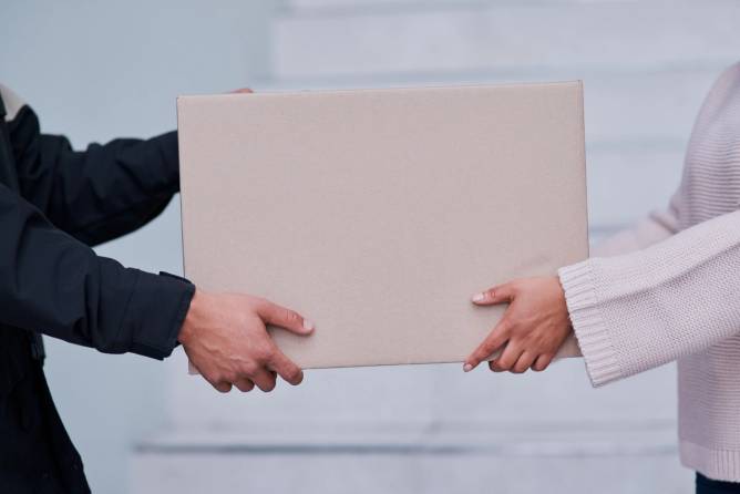 two people's hands holding a package.