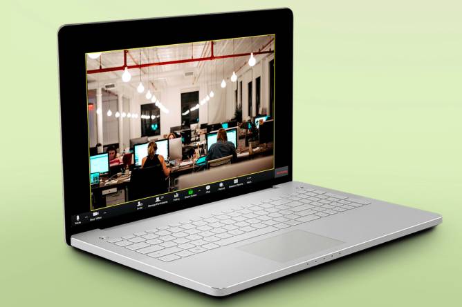 A laptop showing a Zoom meeting screen with workers in an office, backs to camera.