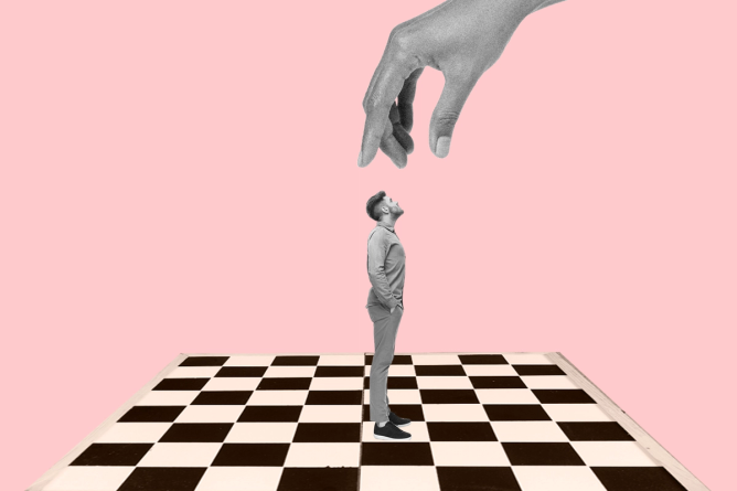 A person standing on chess board with a giant hand reaching down to move them like a chess piece