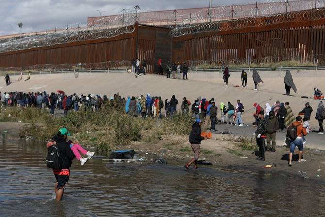 Migrants walk across the Rio Grande to surrender to US Border Patrol agents in El Paso, Texas