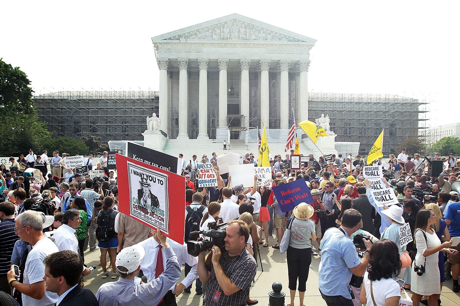 A large crowd holding signs rallies outside of the US Supreme Court Building.