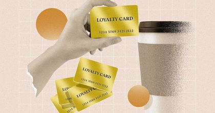 A human hand holding up a gold "Loyalty Card" next to a generic to go cup of coffee