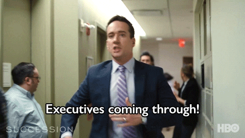 Gif from the HBO series, Succession, with two male actors running in suits down a hall yelling “executives coming through!”