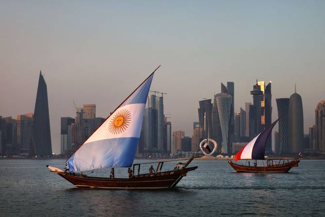 : Boats with sails showing the flags of the nations Argentina and France who will play in the final match sail in-front of the Doha skyline