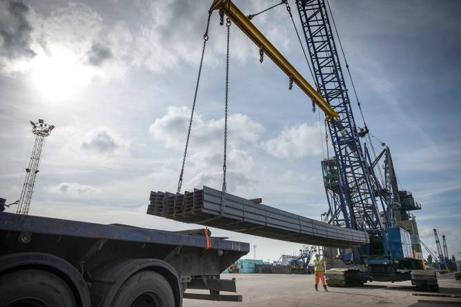 Crane unloading steel from ship in port.