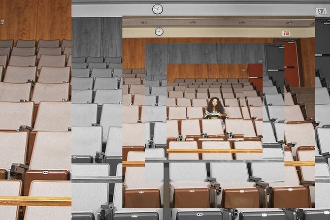 A student sits alone in a college lecture hall, photo illustration.