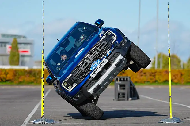 A pickup truck going through a narrow opening on two wheels