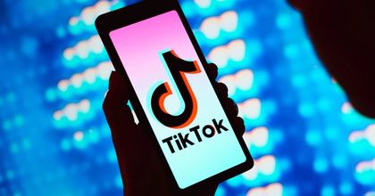 A person holding up a smartphone displaying the TikTok logo