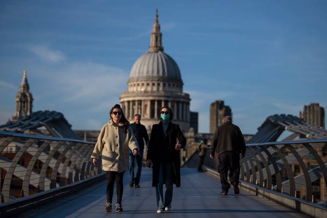 A woman crosses the millennium bridge in front of St Pauls Cathedral
