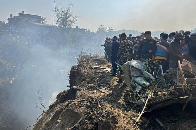 Rescuers and onlookers gather at the site of a plane crash in Pokhara