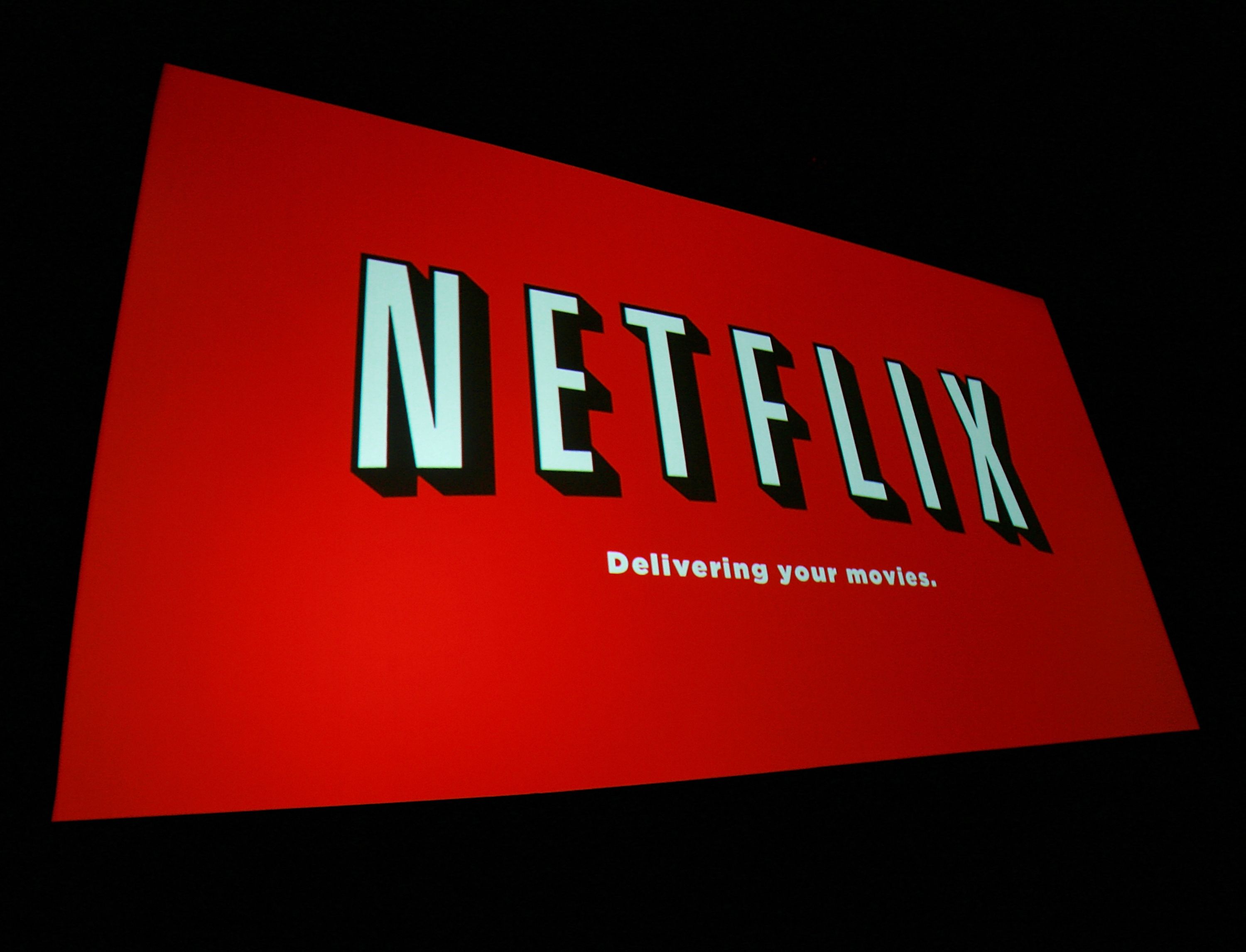 A skewed shot of a Netflix advertisement with their logo and the slogan, Delivering your movies.