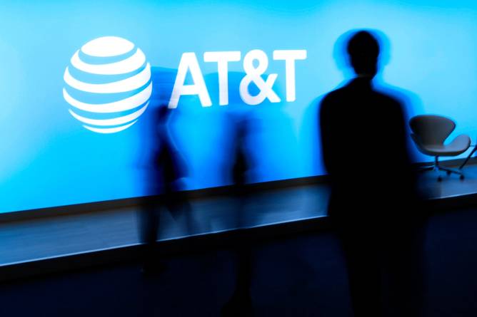 Blurry people silhouettes walking by AT&T logo.