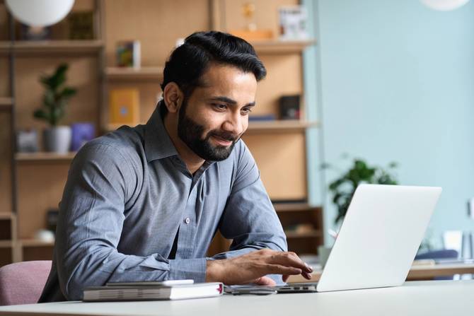Smiling  business man working on laptop at home office