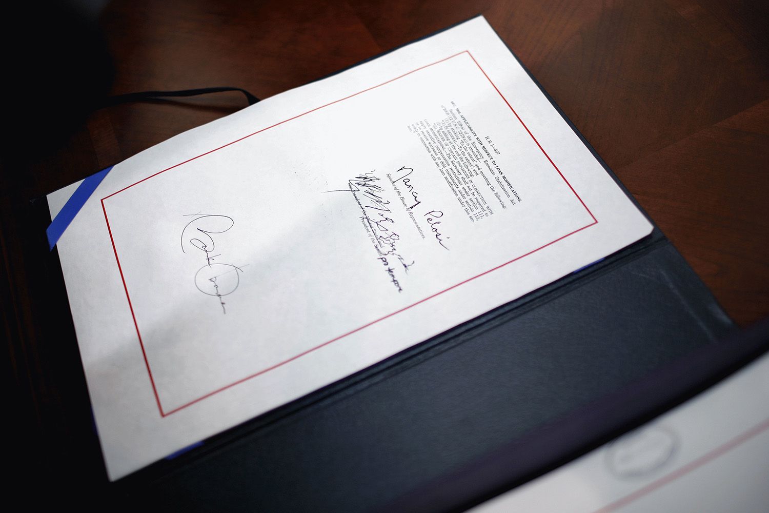 Obama and Nancy Pelosi's signatures on an official document with leather binder.