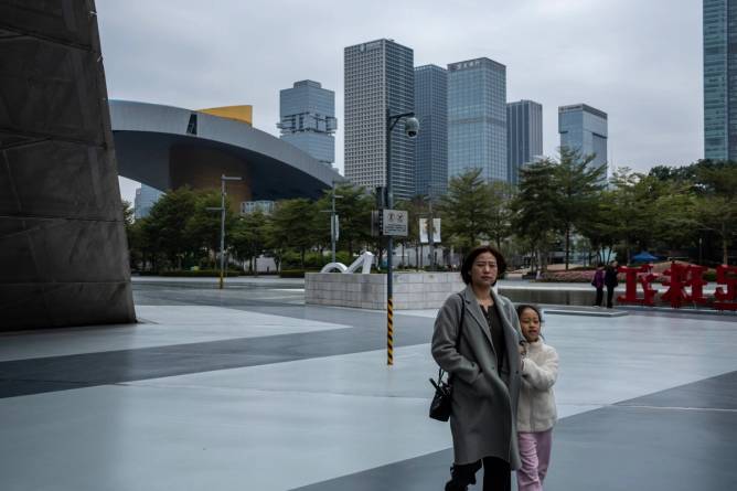 A woman with a child is walking past a security camera in Shenzhen, China, on December 22, 2023.