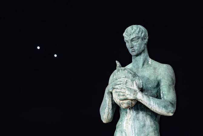 Planets Jupiter and Venus in conjunction are seen after sunset behind a statue in LAquila, Italy, on march 1st, 2023.
