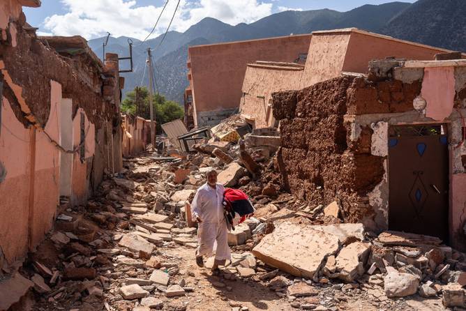 A man carries a blanket as he walks over the rubble of buildings destroyed in yesterday's earthquake, on September 10, 2023 in Ouirgane, Morocco.