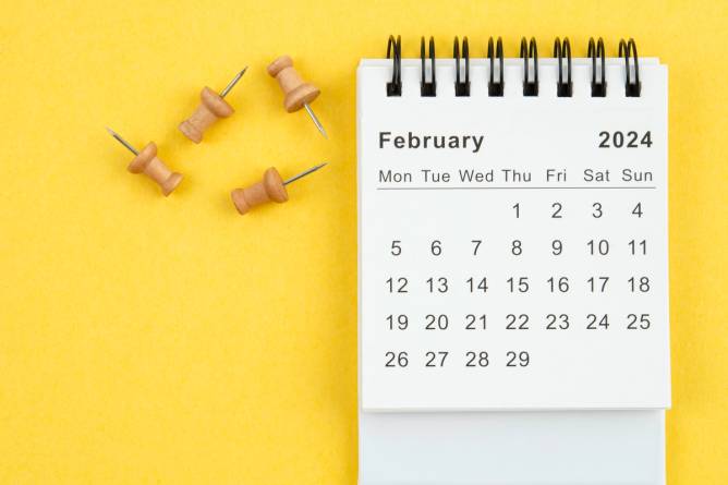 February 2024 calendar with push pins on a yellow background.