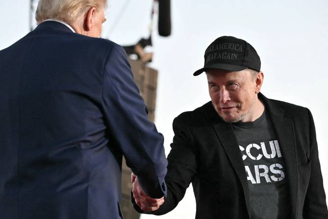 Elon Musk (R) shakes hands with US President Donald Trump during a campaign rally. Credit: Jim Watson/Getty Images