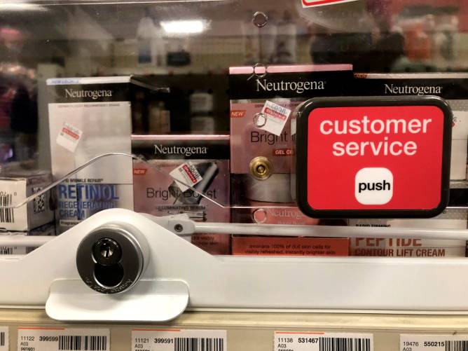 Anti-theft locked merchandise on shelves with customer service button at a CVS.