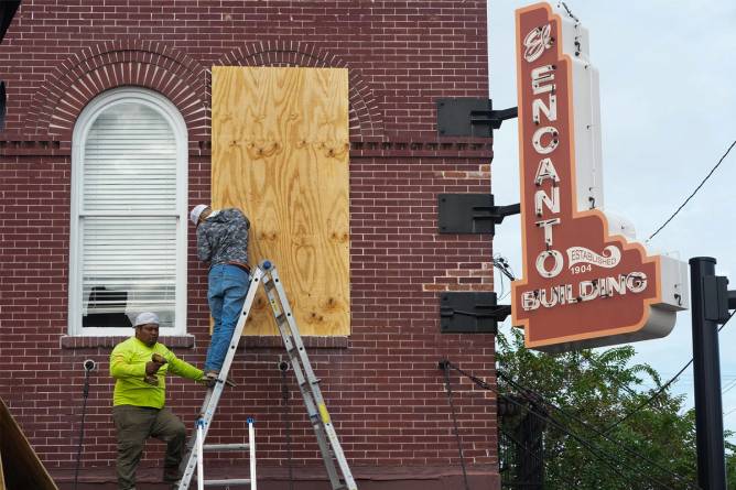 Workers prepare a building for a hurricane