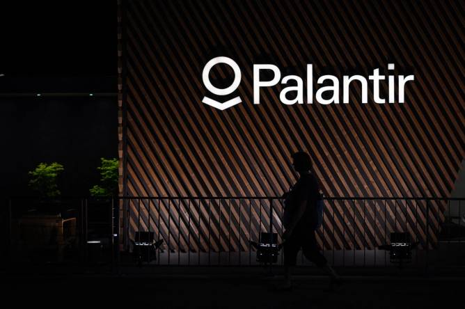 Palantir logo appears on the side of wood slats inside of an office