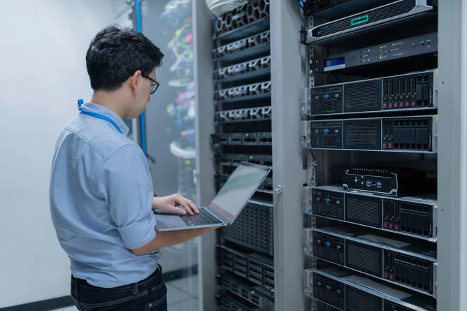 Computer engineer with their laptop in server room at data center.