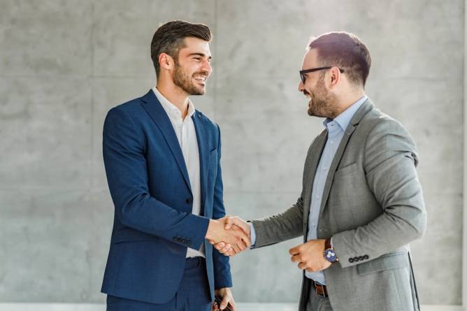 Two white men shake hands