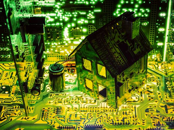 A small model of a home made out of glowing computer motherboards.