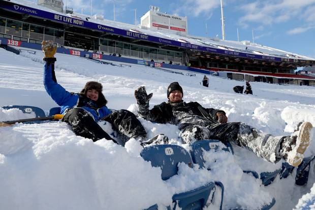 Workers pose as they clear snow from bleacher seats before the game between the Pittsburgh Steelers and the Buffalo Bills at Highmark Stadium on January 15, 2024 in Orchard Park, New York.
