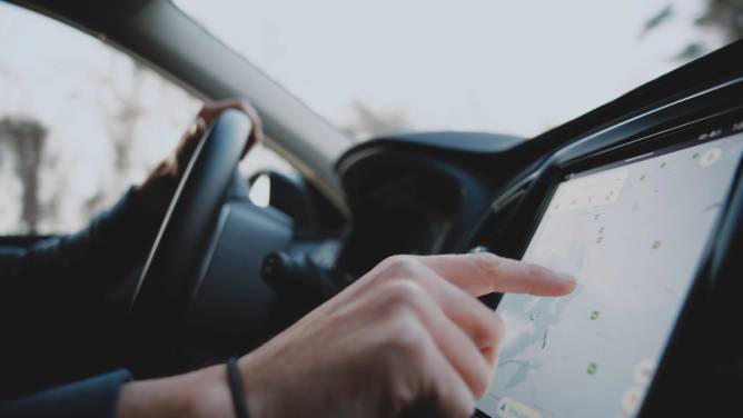 Close-up of hand touching a GPS system in a car.