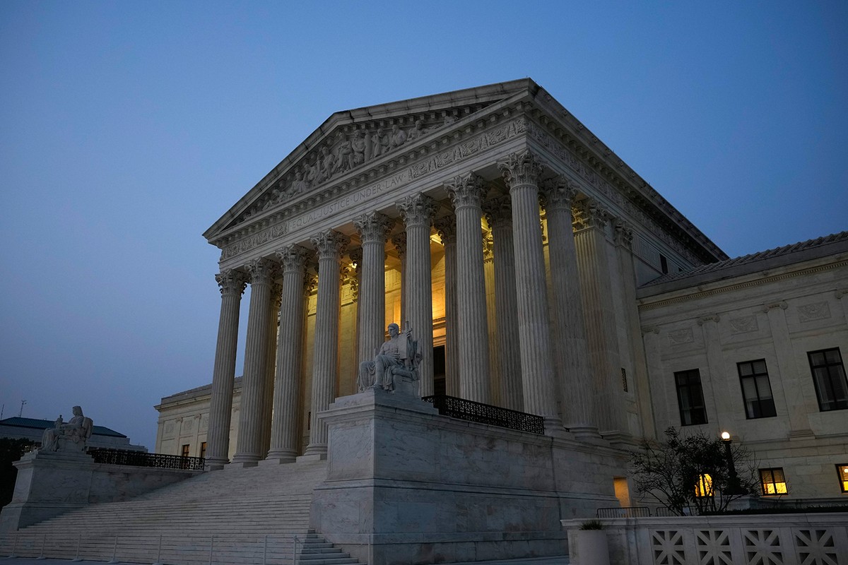 Government building at dusk, glowing light, looming columns.