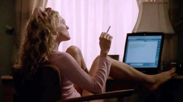 Carrie Bradshaw sitting at her desk smoking.