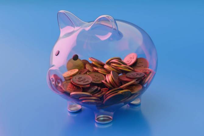 A glass piggy bank showing money inside. 
