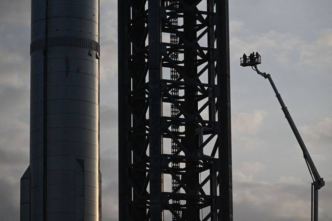 Workers prepare the SpaceX Starship as the sun sets behind them ahead of the launch from the SpaceX Starbase in Boca Chica, Texas on April 18, 2023. 