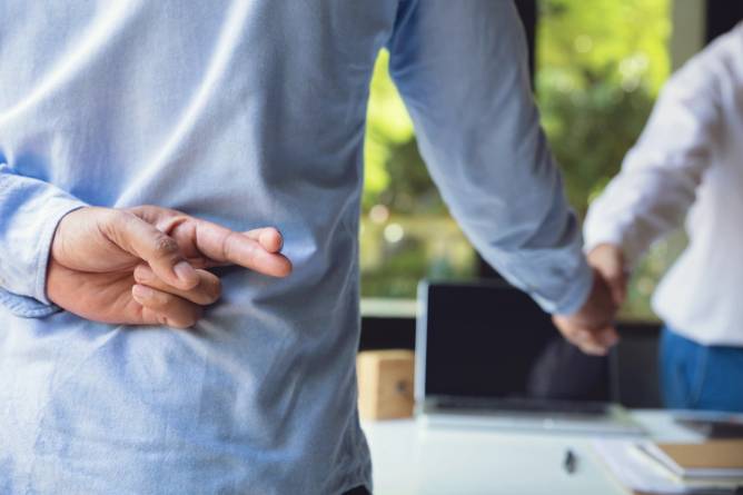 Image of two men handshaking and one man has his fingers crossed behind his back