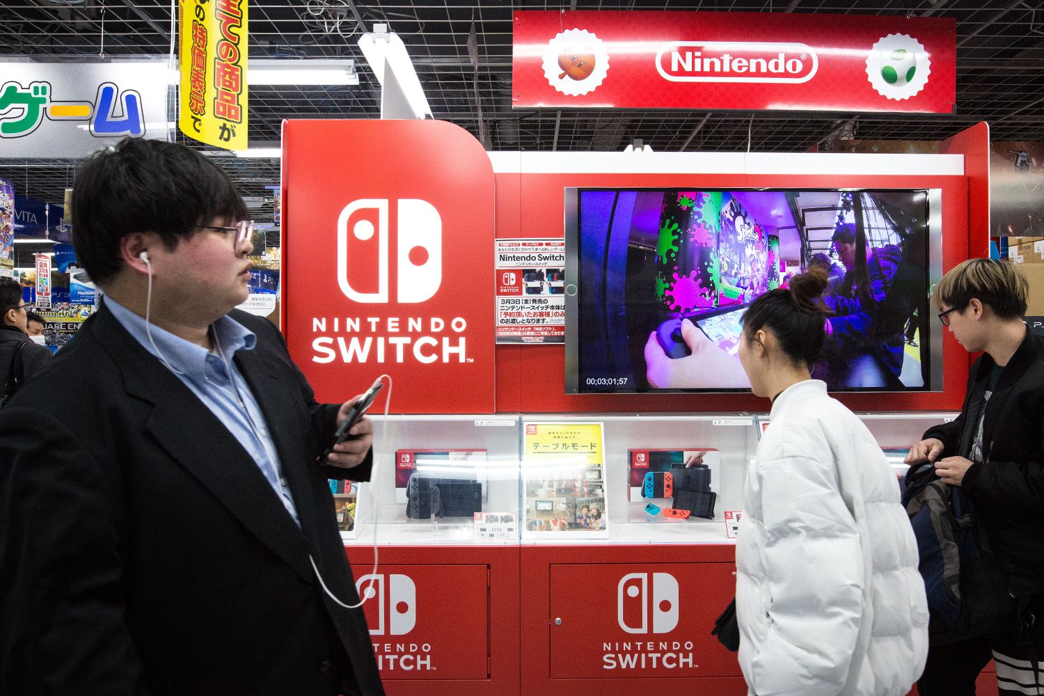 Japanese shoppers walk by a display showcasing the new video game Nintendo Switch console