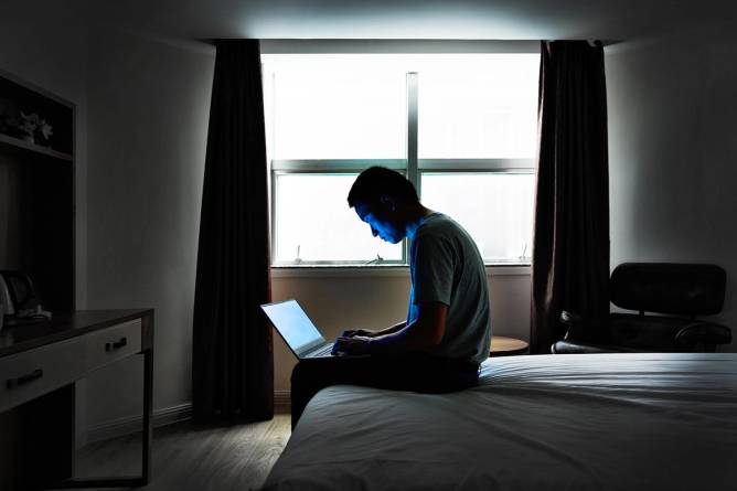 Man looking at bright screen in dark room.