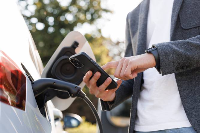 Man charging an EV using an app on his phone.