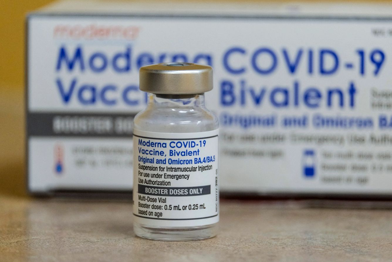 Glass bottle of Moderna's Covid-19 vaccine in front of a box.