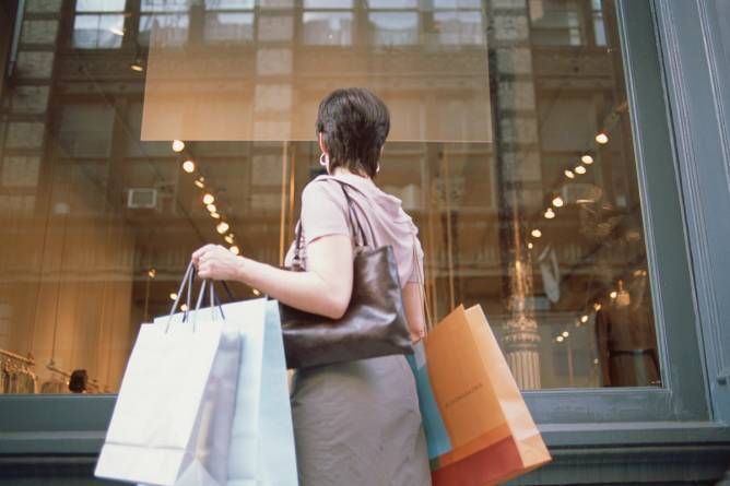 A woman holding shopping bags looks in a window