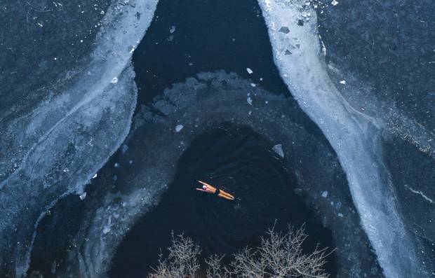 A retired elderly man braved the cold weather to swim in the frozen lake in the park on December 12, 2024