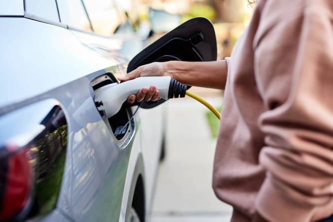 A person plugging in an EV to charge.