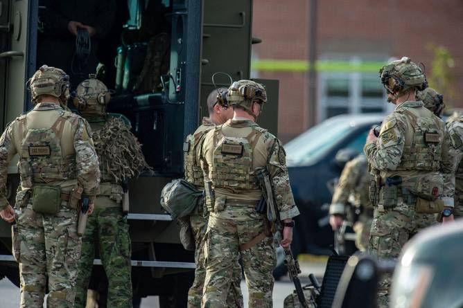 Law enforcement officers gathers as part of a manhunt for Robert Card