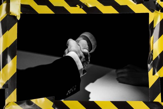 Professionals shake hands through caution tape