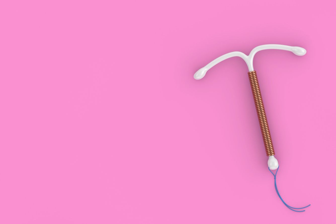 copper IUD on a pink background