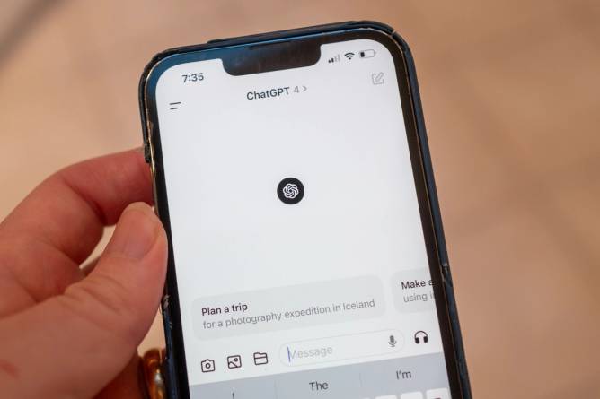 A hand holding an iPhone using ChatGPT.