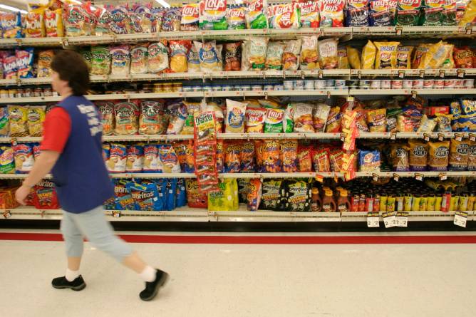 A Walmart employee walks down the chips aisle.