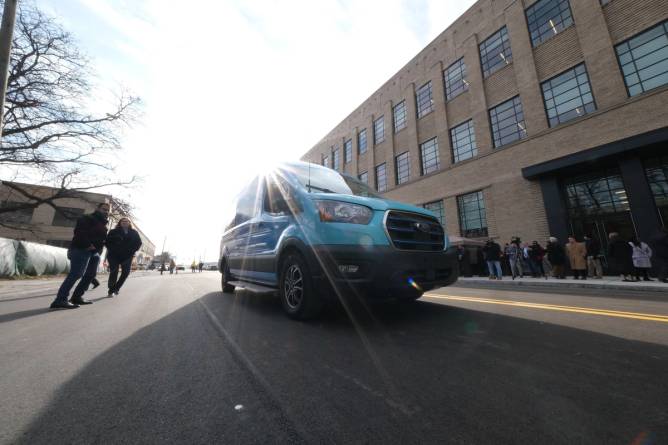 An electric cargo van is pictured on a stretch of roadway equipped for wireless charging.